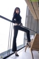 A woman in a black top and black pants posing on a balcony.