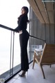 A woman standing on a balcony next to a chair.