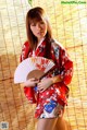 A woman in a red kimono holding a fan.