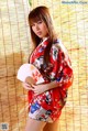 A woman in a red kimono holding a fan.