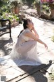 A woman in a white dress sitting on a patio.