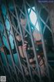 A woman in lingerie standing behind bars in a cage.