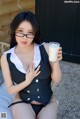 A woman in a black and white dress holding a glass of milk.