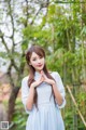 A woman in a blue dress standing in front of a bamboo forest.