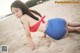 A woman in a red and blue bikini laying on the sand.