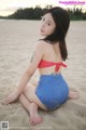 A woman in a red and white polka dot bikini sitting on the beach.