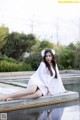 A woman in a white dress sitting on the edge of a pool.