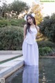 A woman in a white dress standing in a pool.