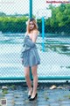 A woman standing in front of a chain link fence.