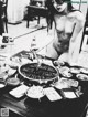 A naked woman standing in front of a table full of food.